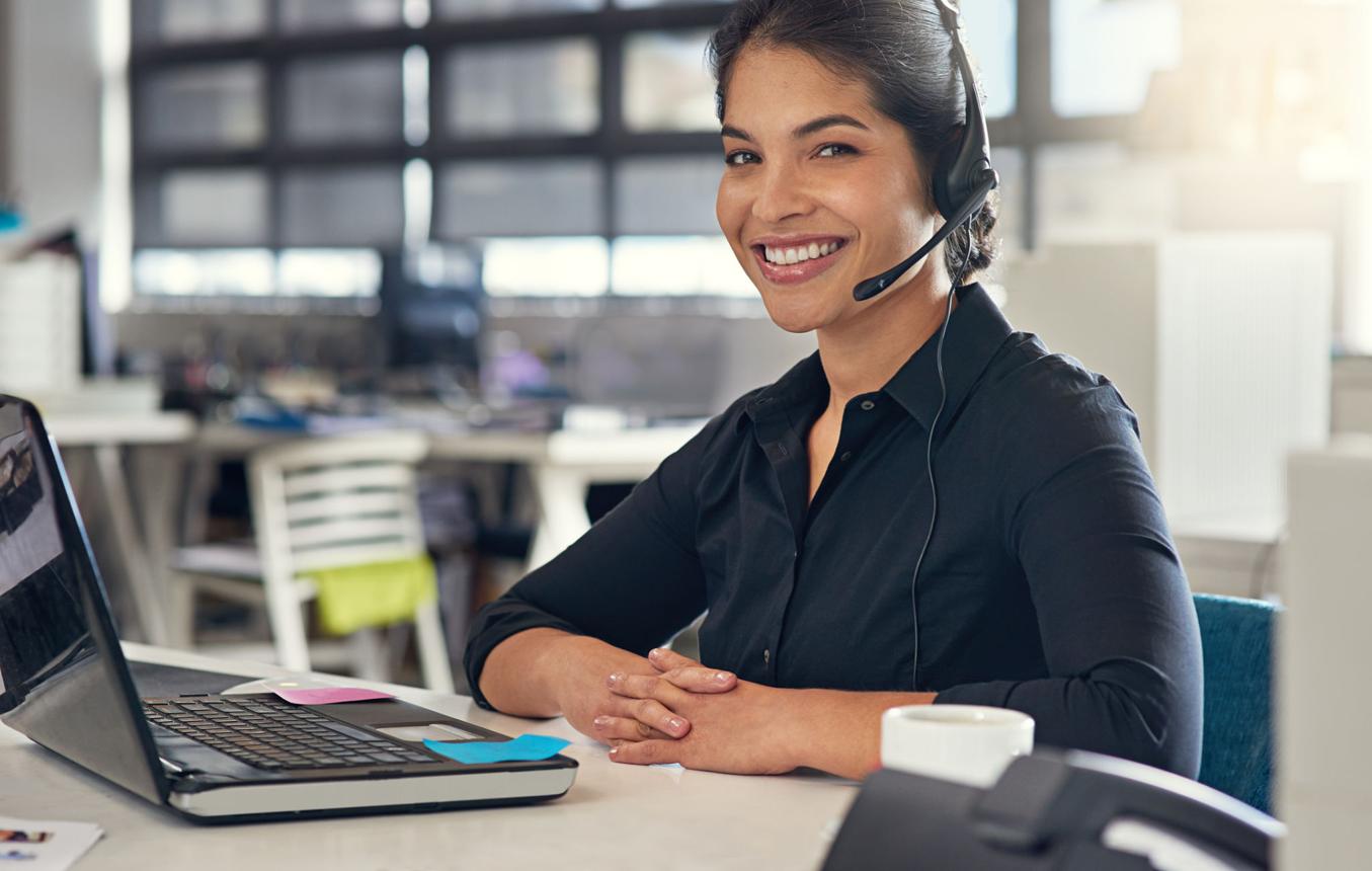 Agente de atención al cliente con auriculares trabajando en un call center bilingüe.